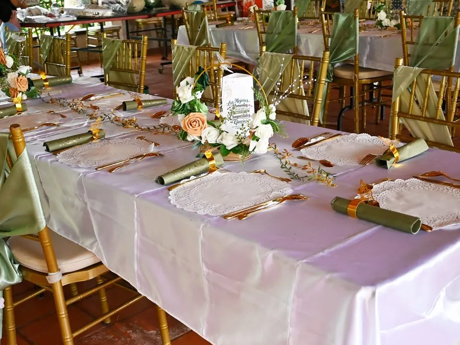 Table de mariage dressée : serviettes, napperons, couverts dorés et centre de table